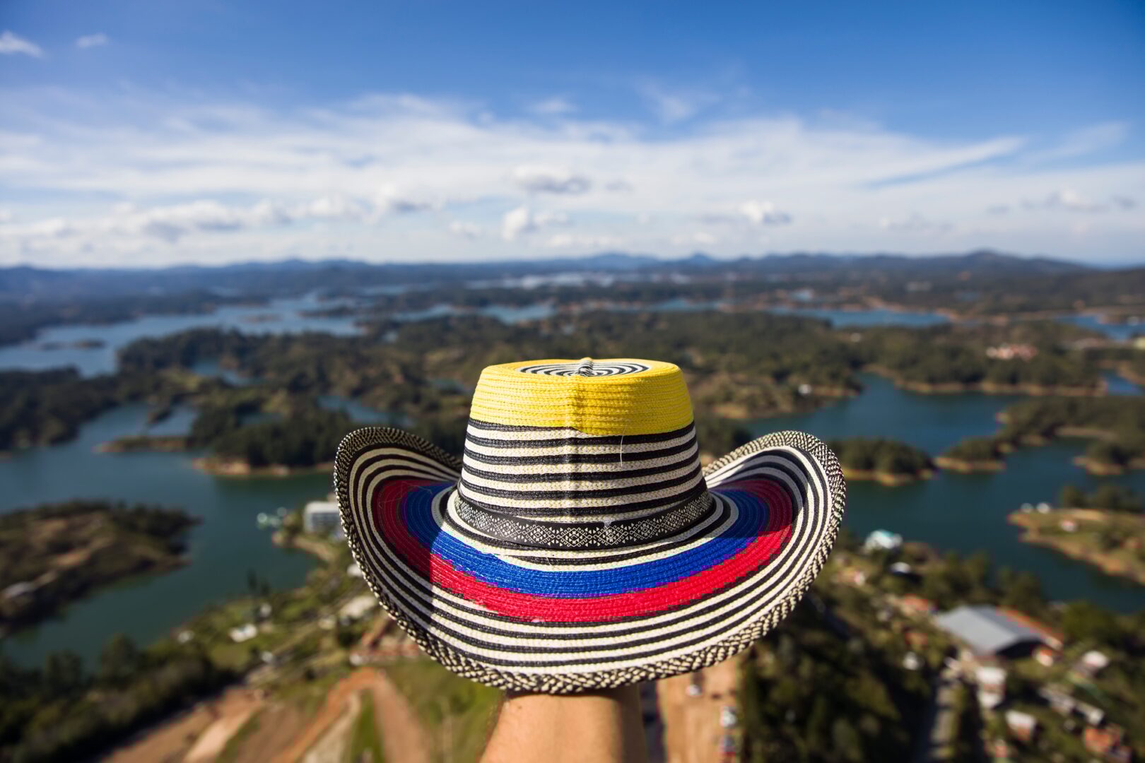 Paquetes a Colombia Todo Incluido desde MX 7 Hand with Colombian hat over Guatape lake in Antioquia, Colombia